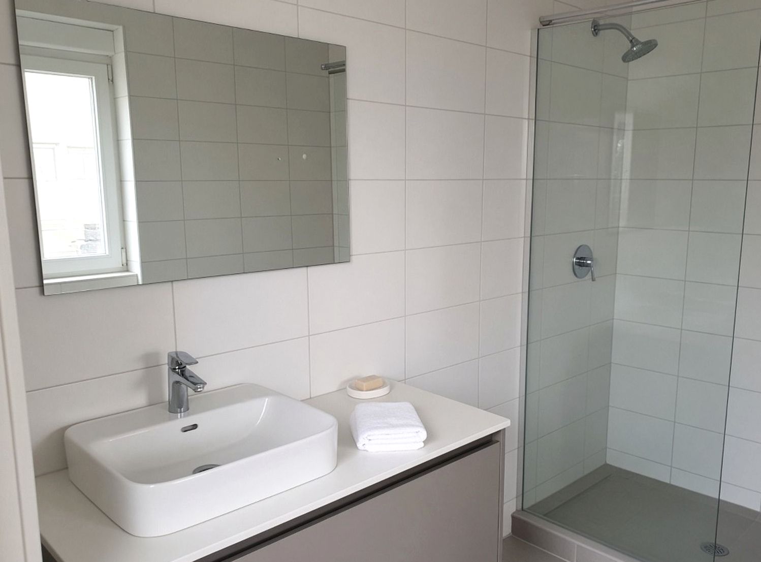 Salle de bain, vasque blanche, douche vitrée, carrelage clair